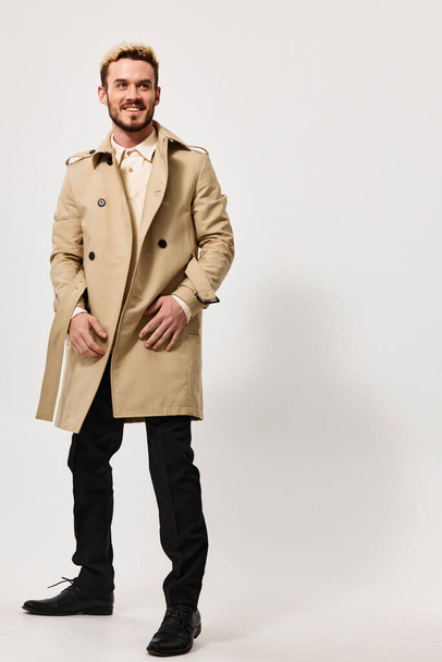 stylish guy in a beige coat holds his hands in his pocket and a blonde in a boot Copy Space - Photo, Image