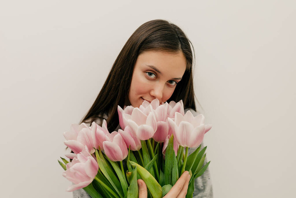 Retrato interno de bela jovem com buquê de flores cor de rosa sobre fundo isolado - Foto, Imagem