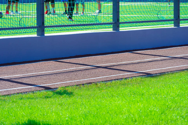 openbaar stadion voor sport - team van voetballers op een voetbalveld, running track closeup en groen gras - Foto, afbeelding
