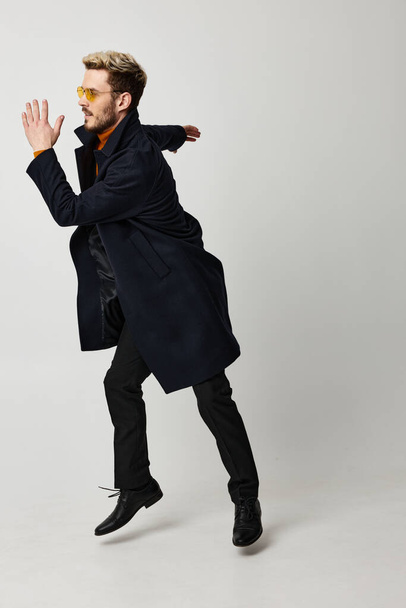 jóképű férfi szemüveges fekete kabát mozgás érzelmek fény háttér - Fotó, kép