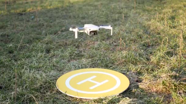 Drone quadcopter aterriza en plataforma amarilla. Lugar de aterrizaje en la pradera. Césped para maniobras. - Imágenes, Vídeo
