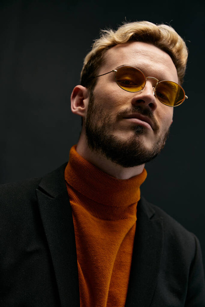 fashionable blond man in a sweater and a jacket on a dark background tilted his head to the side cropped view close-up - Photo, Image