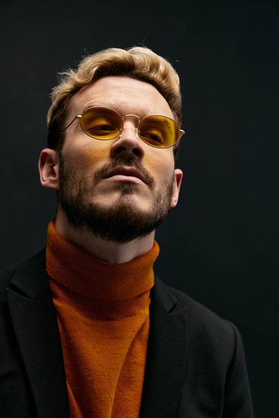 portret van een modieuze man met bril en een oranje trui trend van het najaar nieuwe items - Foto, afbeelding