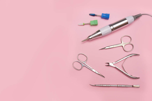 Nail tool. Professional steel manicure and pedicure tools. Manicure scissors, tongs, cutter, clipper and nozzles for polishing nails on a pink background. - Photo, Image