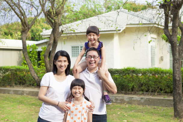 Счастливая семья стоит перед своим домом
 - Фото, изображение