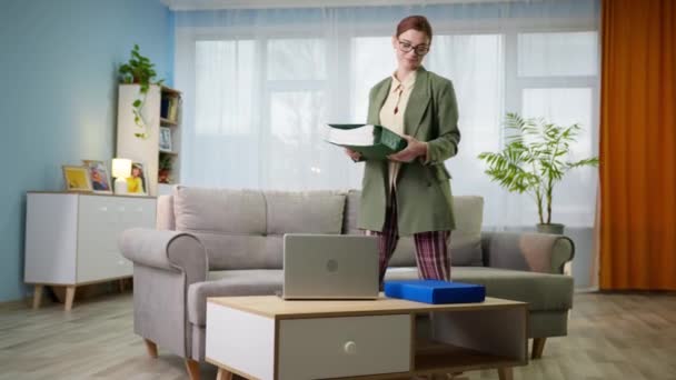 nő mappa dokumentumok kezében és laptop dolgozik távolról otthon beszél videohívás a főnök, miközben ül a kanapén kabát és pizsama nadrág - Felvétel, videó