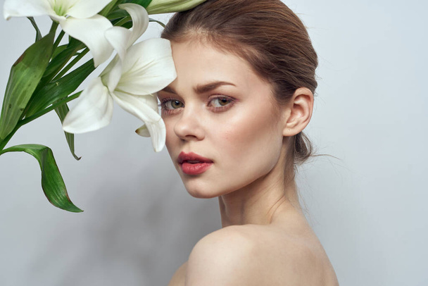 Lady with a bouquet of white flowers on a gray background portrait cropped view close-up - Фото, зображення