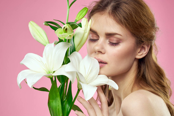 Hermosa mujer con flores en el modelo de retrato de maquillaje de fondo rosa - Foto, imagen