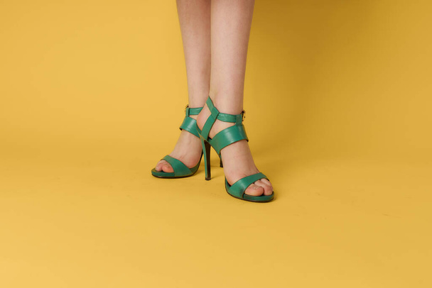 Piernas femeninas zapatos verdes estilo de vida elegante fondo amarillo - Foto, Imagen