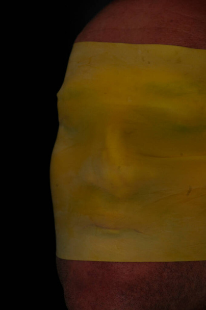 rostro de una persona envuelta en tela amarilla, símbolo de aislamiento, psique humana - Foto, Imagen