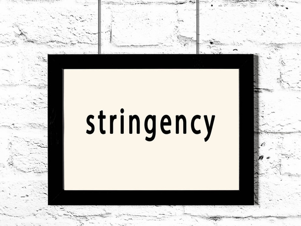 Černý dřevěný rám s nápisem stringency visí na bílé cihlové zdi  - Fotografie, Obrázek