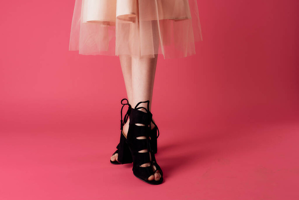 Жіночі ноги чорні модні туфлі на підборах чарівний рожевий фон
 - Фото, зображення