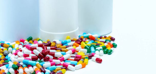 Stapel kleurrijke antibiotica capsule pillen op wazig plastic medicijn flessen. Antibioticaresistentie concept. Antibiotica slim gebruik. Drugsinteracties. Farmaceutische industrie. Polyfarmacie. - Foto, afbeelding
