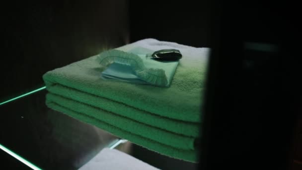 As pilhas de toalhas de banho limpas em prateleiras transparentes com luz LED verde, tiro dolly. - Filmagem, Vídeo
