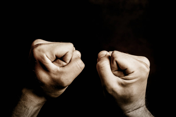 Fist isolated on black. Aggression background. Artistic light male hands point of view. Fighting empty copy space background. Symbol of power. Dark bully background. - Photo, Image