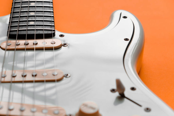 オレンジを基調としたホワイト・エレクトリック・ギターの詳細. - 写真・画像