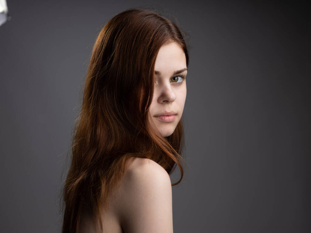 Γυναίκα μοντέλο γκρο πλαν γυμνοί ώμοι κόκκινα μαλλιά σκούρο φόντο - Φωτογραφία, εικόνα