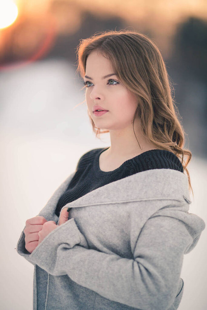 Μια ρηχή εστίαση μιας νεαρής μελαχρινής γυναίκας που φοράει πουλόβερ με γκρι ζακέτα και ποζάρει σε εξωτερικούς χώρους - Φωτογραφία, εικόνα