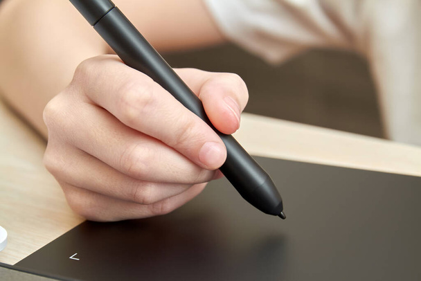 A menina se baseia em um tablet gráfico com caneta. Close-up, foco seletivo - Foto, Imagem
