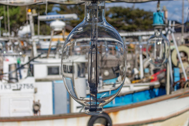 Крупный план электрической ночной рыболовной лампы на рыболовецком судне на реке Тедори в гавани Микава летом, префектура Исикава, Япония. - Фото, изображение