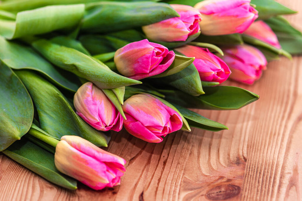 Nők napja. Rózsaszín tulipán csokor fa deszka háttér, másolás helyet, felülnézet. Tavaszi virágok - Fotó, kép