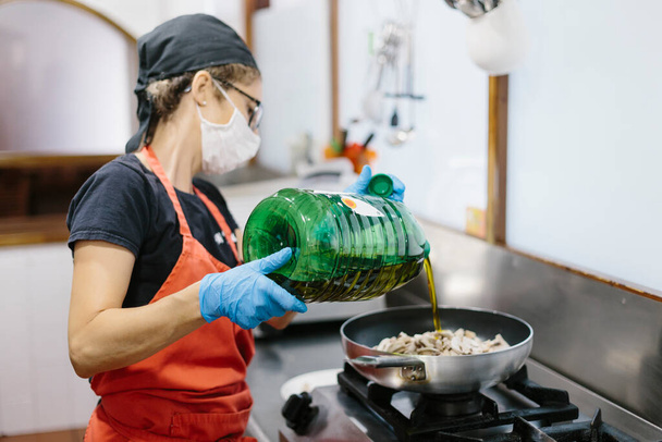 Een kok in een restaurant met een masker als voorzorgsmaatregel tegen het coronavirus dat de maaltijd bereidt.  - Foto, afbeelding