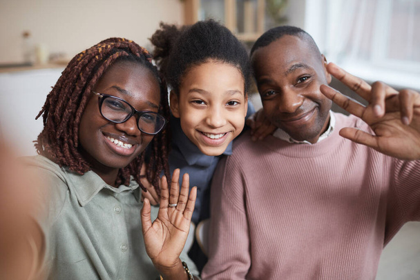 POV-Aufnahme einer glücklichen afroamerikanischen Familie, die in die Kamera lächelt, während sie zu Hause Selfie-Fotos macht oder Videochats nutzt - Foto, Bild