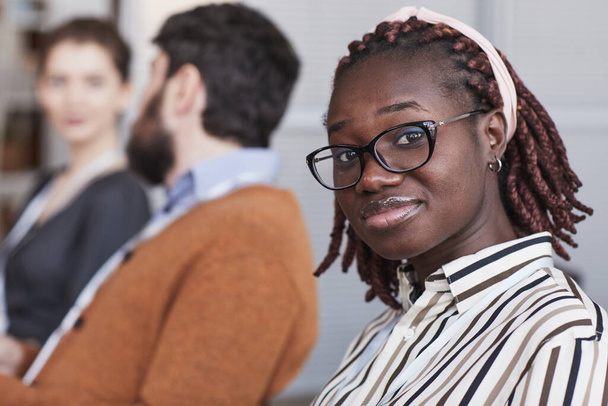 Close up portret młodej Afroamerykanki w okularach i patrząc w aparat podczas siedzenia na widowni na konferencji biznesowej lub seminarium, przestrzeń kopiowania - Zdjęcie, obraz