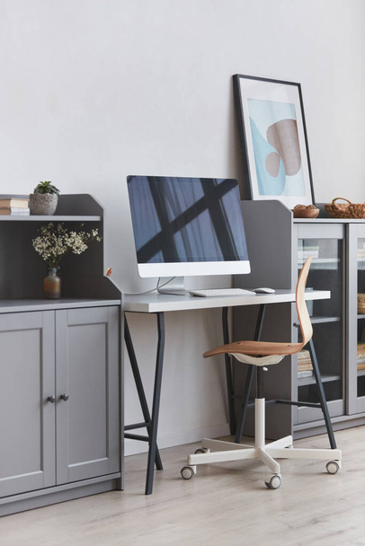 Вертикальное фоновое изображение минимального домашнего рабочего места с деревянным креслом в сером и белом тонах интерьера, копировальное пространство - Фото, изображение