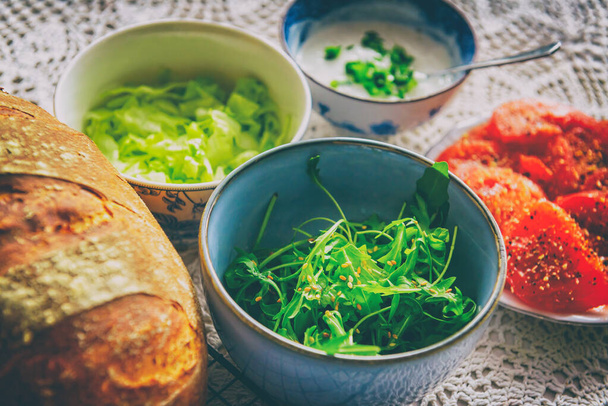 Vegetarian υγιεινό πρωινό που περιέχει σπιτικό ψωμί, ντομάτες λαχανικών, argula με σουσάμι, sald, μαρούλι παγόβουνου και σάλτσα σκόρδου με σχοινόπρασο - Φωτογραφία, εικόνα