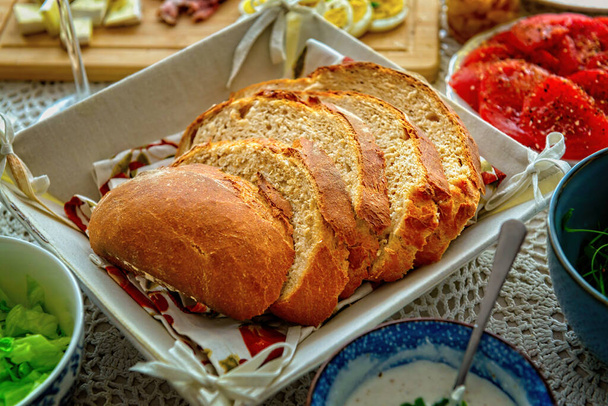 Ένα καρβέλι ψωμί κομμένο σε φέτες. Ένα ευρωπαϊκό, υγιεινό πρωινό που περιέχει σπιτικό ψωμί και ένα λαχανικό, τυρί και αυγό. Ψωμί με βάση το όλυρα και το αλεύρι σίκαλης με προσθήκη σιτάλευρου - Φωτογραφία, εικόνα