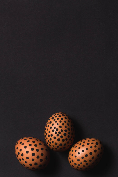 Uova di Pasqua dipinte con puntini neri. Vista dall'alto di uova di Pasqua a forma di corona su superficie nera. Uova dipinte, concettuale creativa Pasqua piatto deporre con spazio copia. Mockup per invito, biglietto di auguri - Foto, immagini