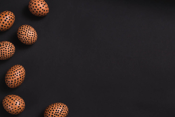 Œufs de Pâques peints à pois noirs. Vue de dessus des œufs de Pâques comme une bordure sur la surface noire. Œufs peints, plan de Pâques conceptuel avec espace de copie, horizontal. Maquette pour invitation, cartes de vœux - Photo, image