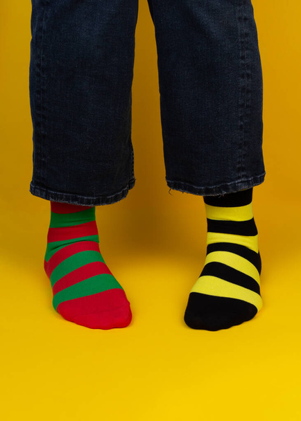 Többszínű, különböző csíkos zoknival ellátott lábak a háttérben fénymásoló hellyel. World Down-szindróma napi háttér. Down-szindróma tudatosság fogalma. - Fotó, kép