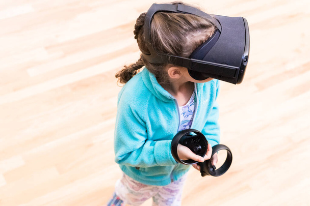 Kislány játszik VR gyerekek játék a nappaliban. - Fotó, kép