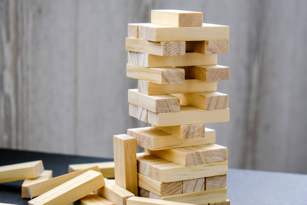 木造ブロックからの建物- jenga 。木製のブロックは、背景に手でゲームをスタック。チームワークの概念。建築モデルとブロックタワー,管理と戦略計画のリスク,成長ビジネス成功プロセス - 写真・画像