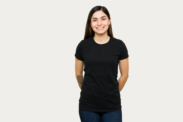 Portrait of a cute young woman smiling and wearing a mock up black t-shirt. Beautiful woman in a t-shirt for design print - Photo, Image