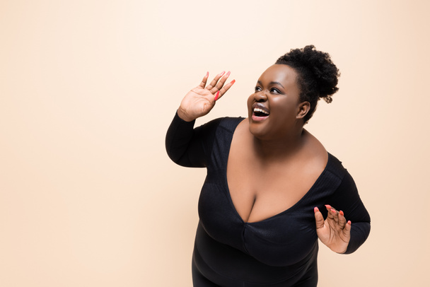 emocionado africano americano más tamaño mujer mirando lejos aislado en beige  - Foto, Imagen