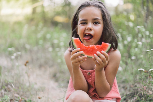 Das Mädchen isst eine Wassermelone. Sommerstimmung in der Kindheit. - Foto, Bild
