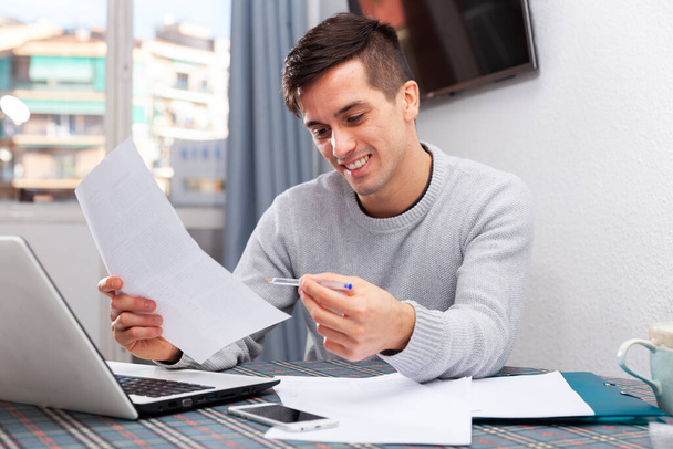 Smiling male with laptop analyzing domestic budget - Fotografie, Obrázek