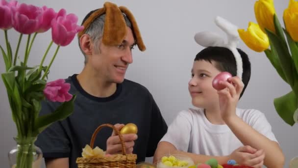 Pai e filho felizes estão segurando ovos pintados e sorrindo. Preparando para a Páscoa. 4K - Filmagem, Vídeo