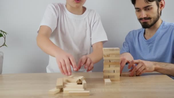 Ребенок строит башню из деревянных кирпичей. Настольные игры для всей семьи. Семейное веселье дома. 4K - Кадры, видео