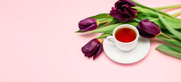 Flores púrpuras y una taza de café blanco sobre un fondo rosa. Una hermosa pancarta con espacio para copiar. - Foto, imagen