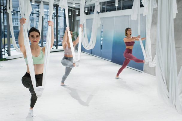 молоді спортивні жінки розігріваються мухами йоги в тренажерному залі
 - Фото, зображення