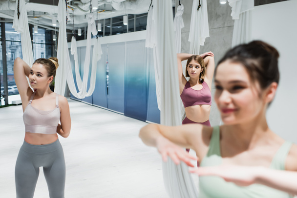 grupo de esportistas aquecendo perto de redes aéreas de ioga, foreground borrado - Foto, Imagem