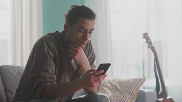 Hombre joven se relaja usando Smartphone - Metraje, vídeo