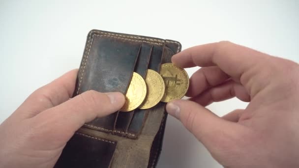 Κοντινό πλάνο του ανθρώπου που βάζει bitcoin στο πορτοφόλι πάνω από λευκό φόντο - Πλάνα, βίντεο