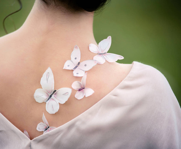 Handmade butterflies made of natural silk on the shoulder. Butterfly wings with soft focus in blur - Φωτογραφία, εικόνα