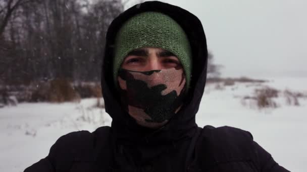 Kapüşonlu ve eşarplı genç adamın selfie 'si. Kar yüzünden gözlerini kapatıyor. - Video, Çekim