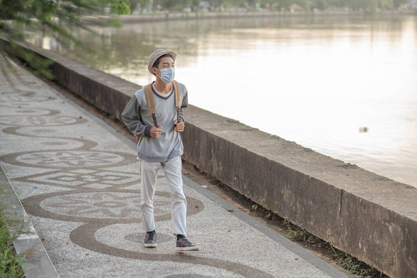 Teenager man walking outside the river on the road with protective face mask - Photo, Image